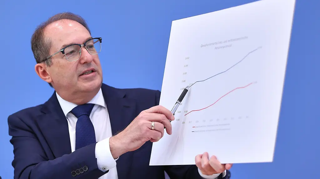 Bundesinnenminister Dobrindt mit einem großem Blatt in der Hand. Darauf zu sehen eine Grafik.