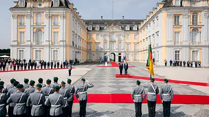Outside Augustusburg Palace, Federal Chancellor Friedrich Merz welcomes French President Macron with military honours.