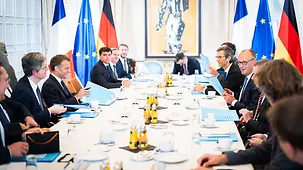 The German and French delegations seated at a long conference table.
