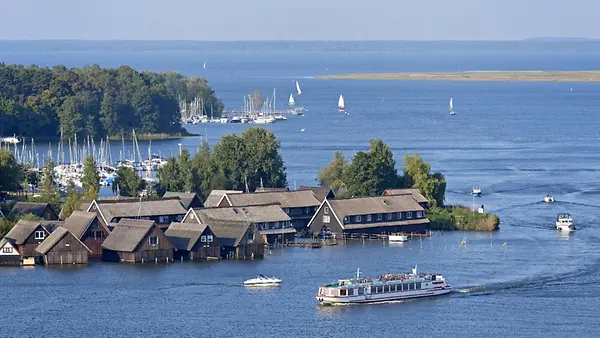 Ausblick über die Müritz mit Häusern am Ufer und Boten auf dem Wasser.