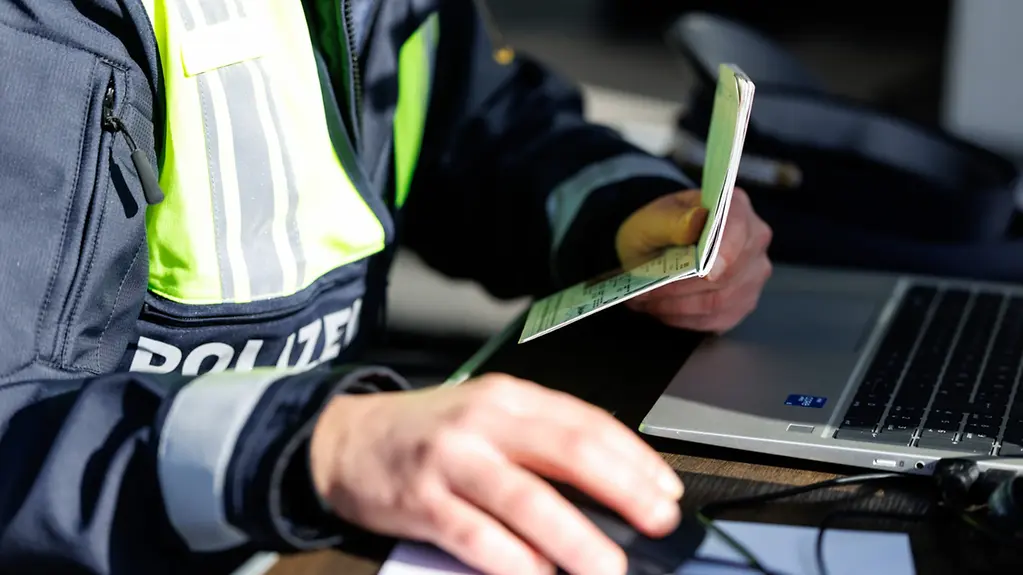 Hände eines Polizisten an einem Polizeilaptop