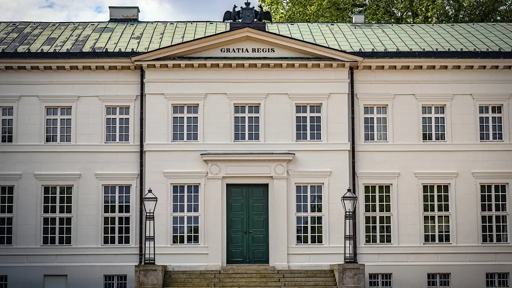 Frontansicht des Schloss Neuhardenbergs: Weißer Barockbau mit grünem Dach.