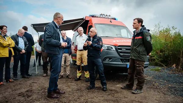 Kanzler Merz mit Einsatzkräften im Hürtgenwald. 