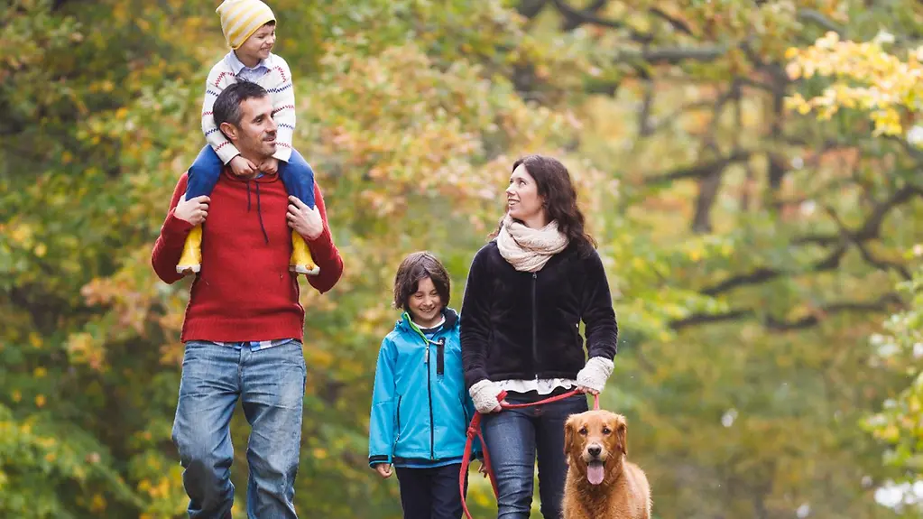 Vierköpfige Familie mit Hund beim Spaziergang