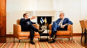 Le chancelier fédéral Friedrich Merz et Petteri Orpo s’entretiennent, assis dans des fauteuils devant une cheminée.