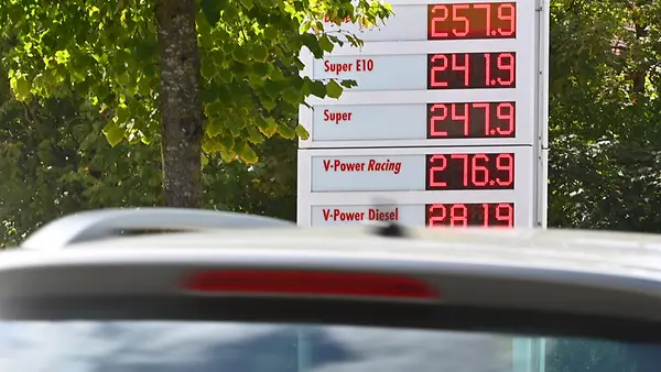 Heck eines PKW im Hintergrund sieht man die Anzeigentafel einer Tankstelle.
