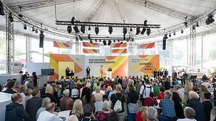 Bundesverteidigungsminister Boris Pistorius auf der Bühne im Dialogzelt mit Besucherreihen im Vordergrund..