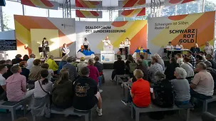 Mitglieder des Zolls auf der Bühne des Dialogforums. im Vordergrund Besucherinnen und Besucher.