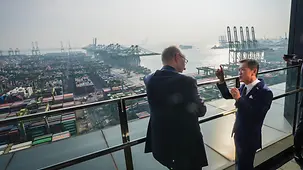 Bundeskanzler Friedrich Merz im Gespräch mit Blick über das Hafengelände von PSA Horizons.