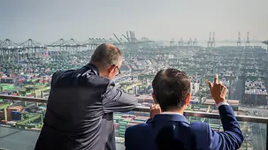 Bundeskanzler Friedrich Merz lehnt an einem Geländer und schaut auf den Hafen von PSA Horizons.