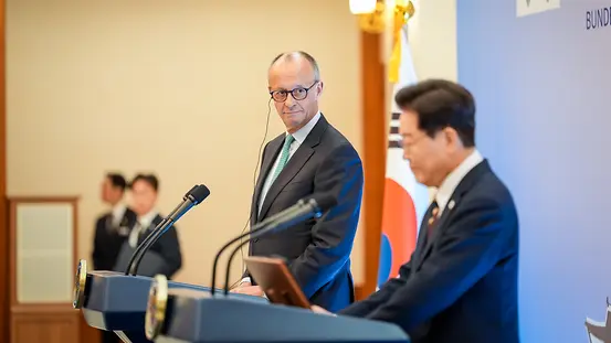 Bundeskanzler Merz und Südkoreas Präsident Lee Jae-myung bei einer Pressekonferenz hinter Rednerpulten.