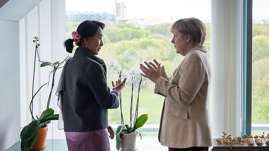 Bundeskanzlerin Angela Merkel erklärt der myanmarischen Oppositionsführerin Aung San Suu Kyi am Fenster der Kanzleramtes die Umgebung.