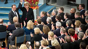 Bundeskanzlerin Merkel und der französische Präsident Hollande grüßen gemeinsam in den Saal.