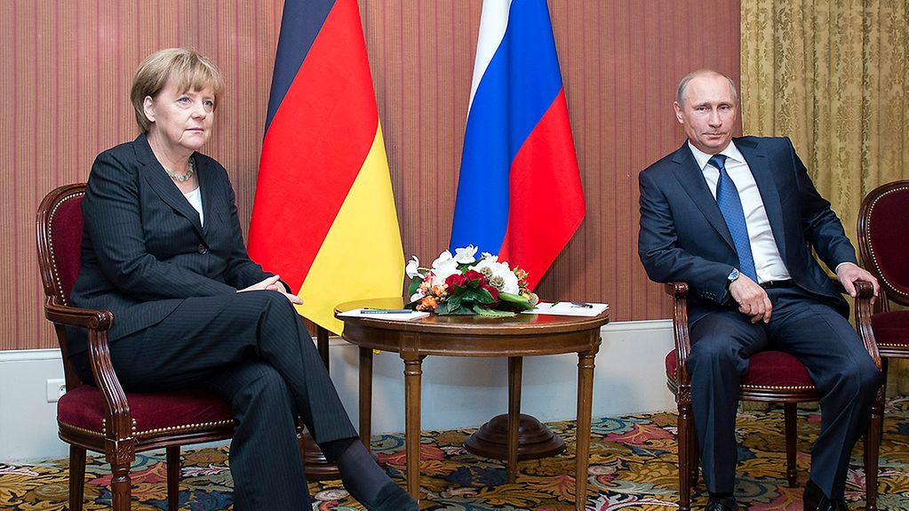 Bundeskanzlerin Angela Merkel sitzt neben dem russischen Präsidenten Wladimir Putin.