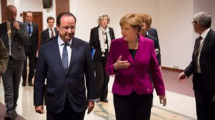Chancellor Angela Merkel walks beside French President François Hollande.