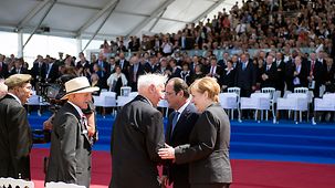 Bundeskanzlerin Angela Merkel und der französische Präsident François Hollande begrüßen Kriegsveterane.