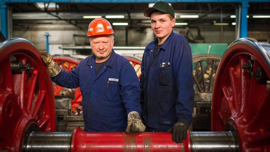 Mitarbeiter des Dampflokwerk Meiningen posieren am Radsatz einer Dampflok.13.02.2013. Erfahrung ist Zukunft Wirtschaft Mittelstand