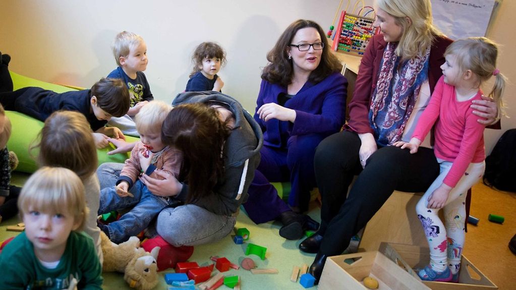 Bundesfamilienministerin Manuela Schwesig (r.) und Bundesarbeitsministerin Andrea Nahles sitzen in Berlin in einer Kindertagesstätte in Friedrichshain mit Kindern und Erzieherinnen zusammen.