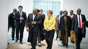 Chancellor Angela Merkel talks with Ghana's President, John Dramani Mahama, as they walk through the Federal Chancellery.