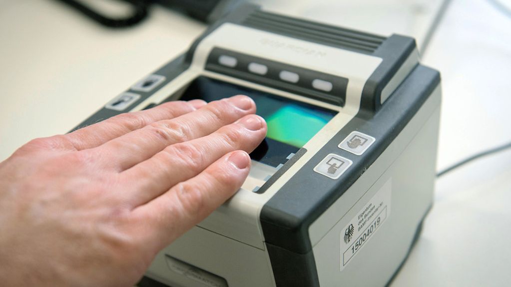 Ein Zollbeamter legt seine Hand auf ein Gerät zur Registrierung der Fingerabdrücke.
