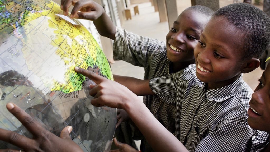 Schulkinder aus Burkina Faso halten eine Weltkugel.