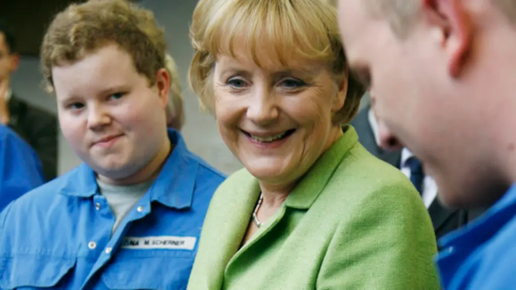 Bundeskanzlerin Angela Merkel und Norddeutsche Affinerie Chef Bernd Drouven unterhalten sich mit Auszubildenden bei der Industriemechanik- mit Auszubildenden beim Rohrleitungsbau.