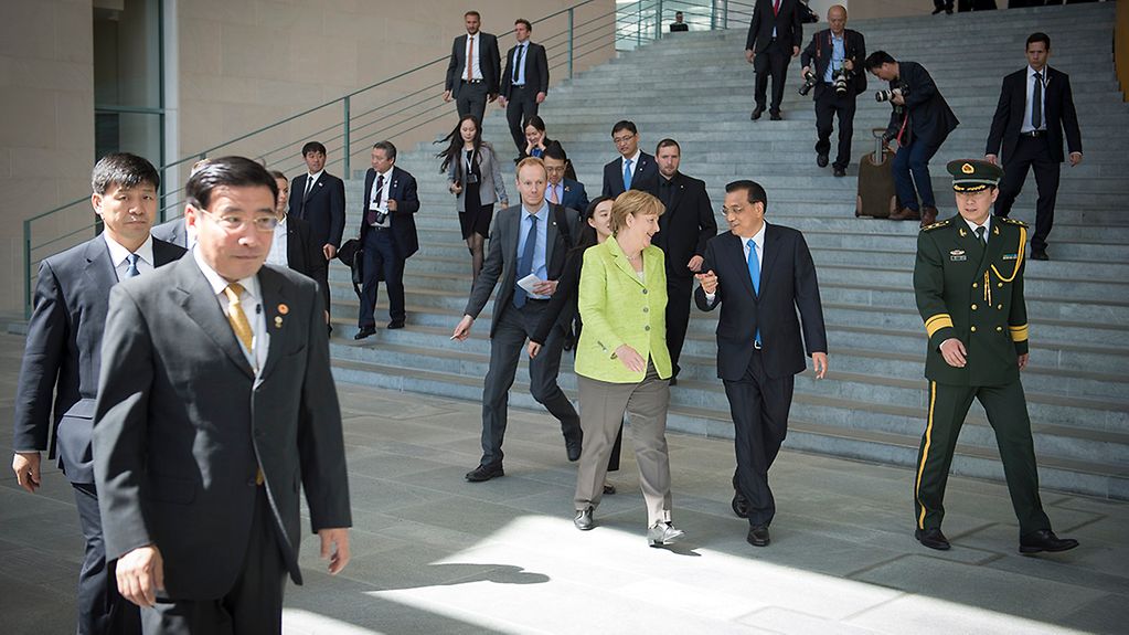 Chancellor Angela Merkel walks through the Federal Chancellery next to Chinese Prime Minister Li Keqiang.
