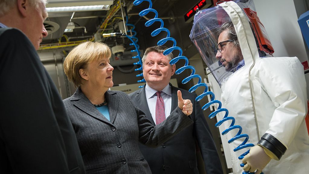 Bundeskanzlerin Angela Merkel lässt sich beim Besuch eines S4-Hochsicherheitslabors im Robert-Koch-Institut das neue Labor erklären.