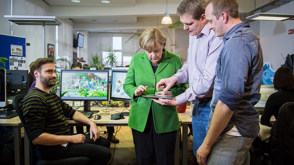 Kanzlerin Merkel (2.v.l.) lässt sich vom Wooga-Geschäftsführer, Jens Begemann (2.v.r.), einige Social-Games zeigen
