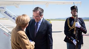 Greek Prime Minister Antonis Samaras greets Chancellor Angela Merkel at the airport.
