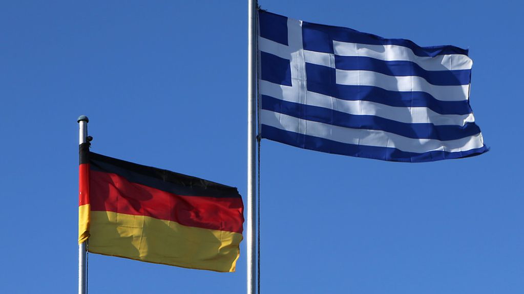 The German and Greek flags blow in the wind.