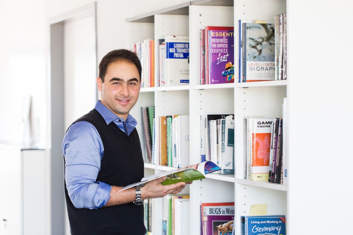Soroosh Eghbali, Mitarbeiter bei der ModuleWorks GmbH in Aachen steht vor einem Bücherregal in der Unternehmensbibliothek.