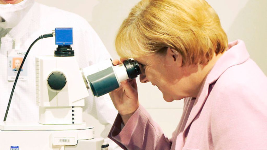 Bundeskanzlerin Angela Merkel an einem Mikroskop am Stand eines Chipherstellers