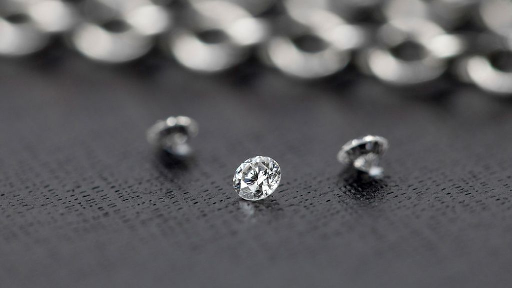 Drei künstlich hergestellte einkristalline Diamanten liegen auf einer grauen Unterlage.