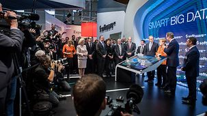 Karl-Heinz Streibich, CEO of Software AG, explains to Chancellor Angela Merkel and British Prime Minister David Cameron what his company does.