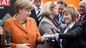 Claudia Breidbach shakes an artificial bionic hand with Chancellor Angela Merkel.