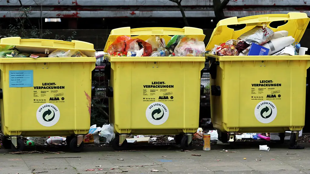 Drei überquellende gelbe Müllcontainer für Verpackungsmüll