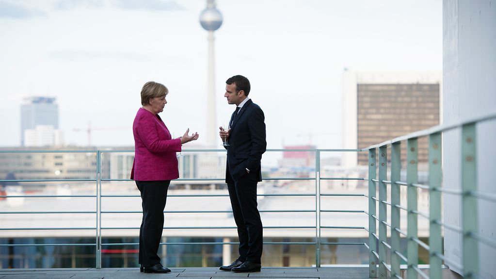 Bundeskanzlerin Angela Merkel und Frankreichs Staatspräsident Emmanuel Macron unterhalten sich auf der Terrasse im Bundeskanzleramt.