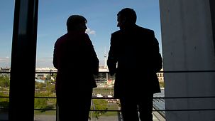 Bundeskanzlerin Angela Merkel spricht mit Frankreichs Präsident Emmanuel Macron auf einer Terrasse im Bundeskanzleramt.