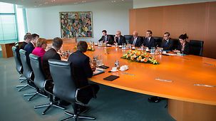 Chancellor Angela Merkel and French President Emmanuel Macron sit opposite one another during talks at the Federal Chancellery.