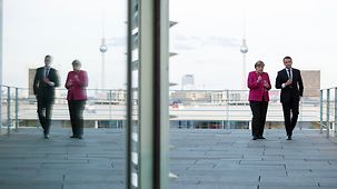 Chancellor Angela Merkel stands with French President Emmanuel Macron on one of the terraces of the Federal Chancellery.