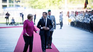 Chancellor Angela Merkel and French President Emmanuel Macron walk into the Federal Chancellery.
