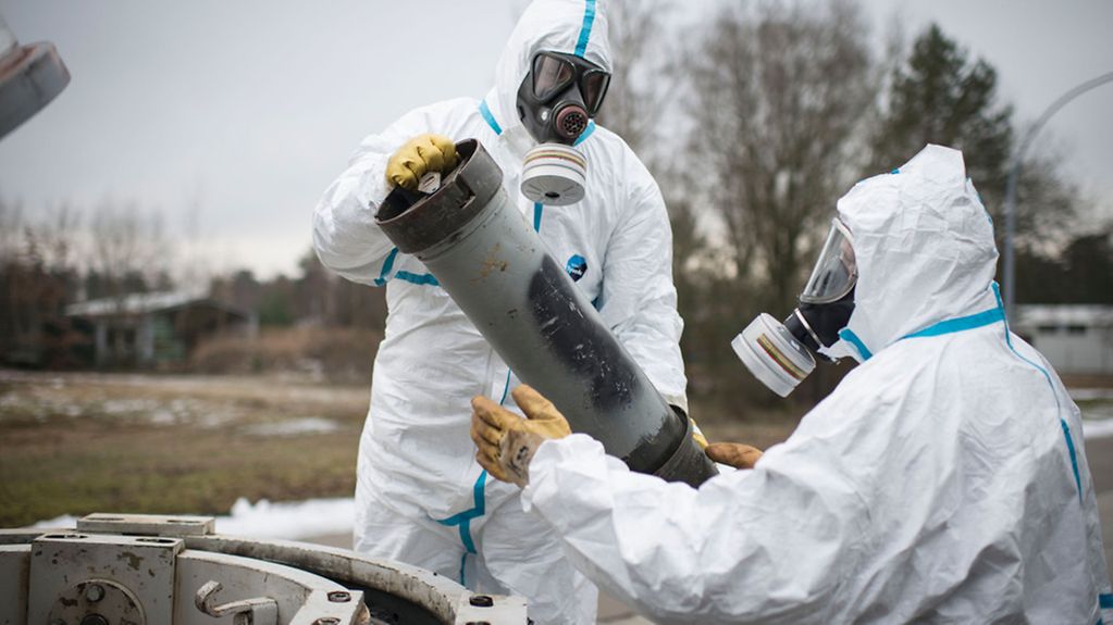 Employees of GEKA association specialised in the disposal of chemical warfare agents and hazardous military waste) wearing protective overalls demonstrate how a dummy container with potential chemical weapons is taken out of a transport container.
