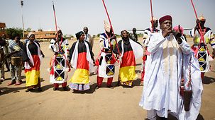 Dancers and musicians welcome the Chancellor to the Niger.