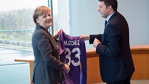 Italiens Ministerpräsident Matteo Renzi überreicht der Bundeskanzlerin Angela Merkel ein Trikot Fußballers Mario Gomez vom AC Florenz.