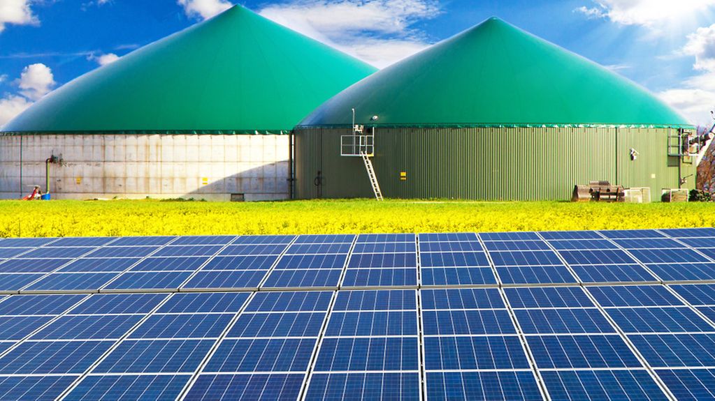 Solaranlage auf einem Feld vor einer Biogasanlage