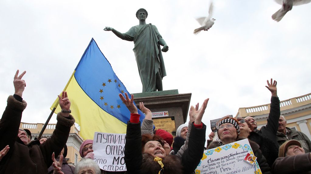 Frauen mit ukrainischer Flagge lassen Tauben fliegen.