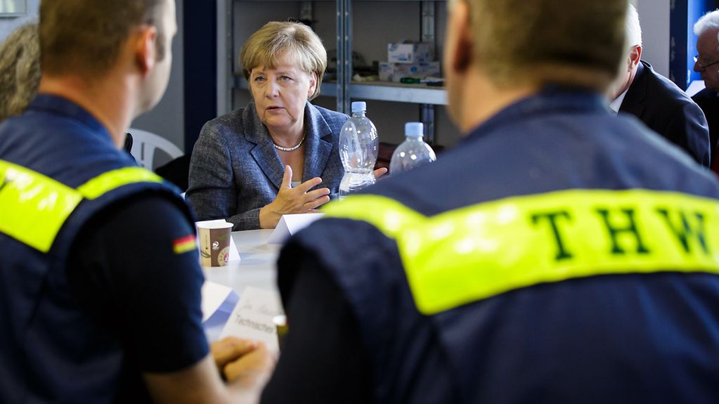 Bundeskanzlerin Angela Merkel beim Besuch einer Flüchtlingsunterkunft im Gespräch mit Helfern.
