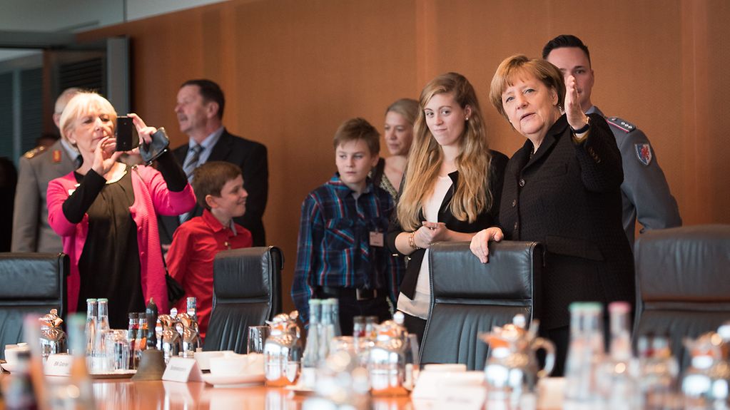 Bundeskanzlerin Angela Merkel führt die Gäste durch den Kabinettssaal.