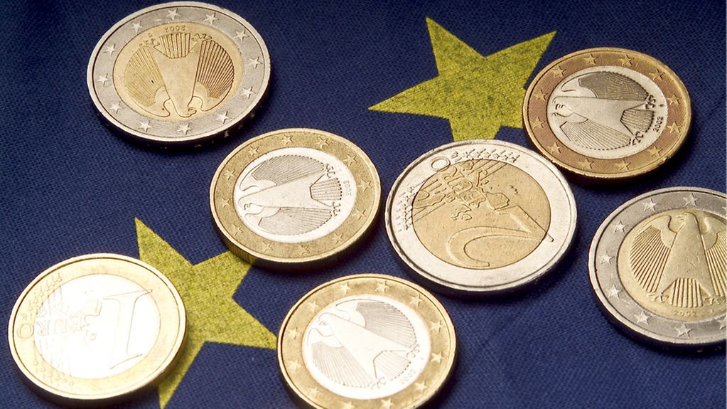 Euromünzen liegen auf einer Europafahne